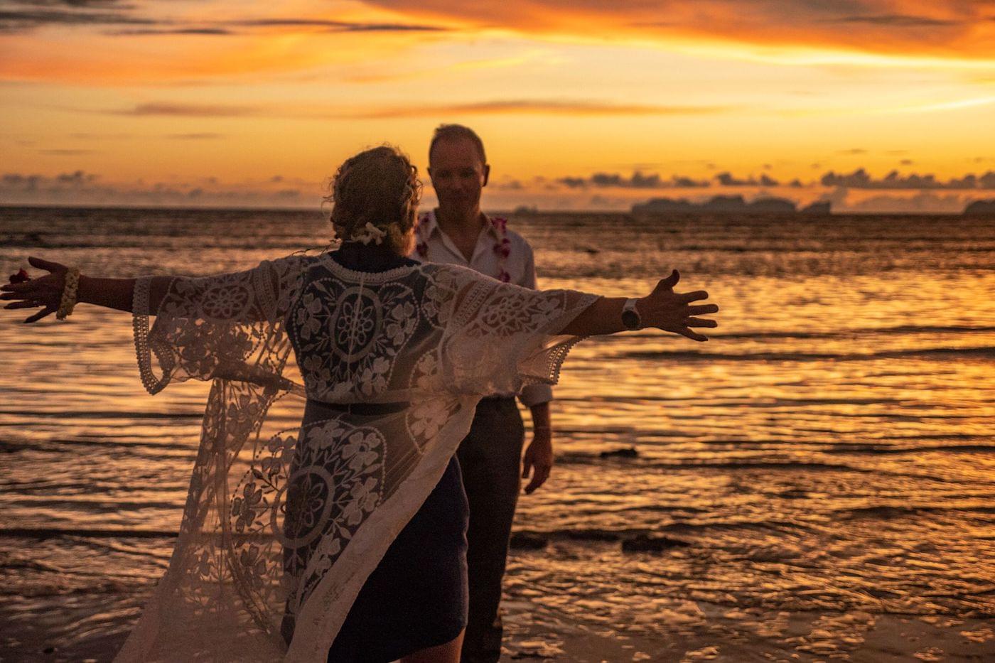 Bride and goom celebrating on beach at sunset